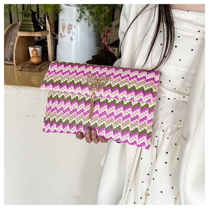 Detail of woven straw clutch featuring colorful chevron patterns and a gold butterfly clasp