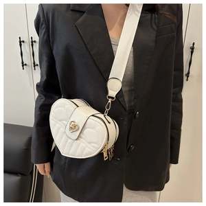 Detail of white heart-shaped crossbody bag with wing texture and gold metal lock