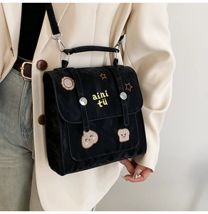 Détail d'un sac bandoulière en nylon noir avec broderies d'étoiles et de toast