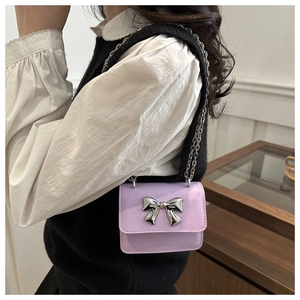 Lavender mini square bag with silver bow buckle and chain strap on white ruffle shirt