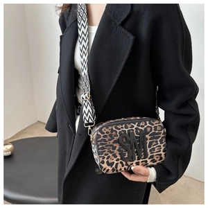 Detail of leopard print camera bag with bold SM logo and woven wide shoulder strap