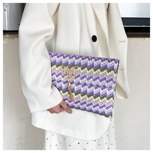 Detail of woven straw clutch with purple zigzag pattern, gold butterfly and long tassels