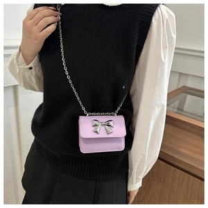 Detail of a mini lavender crossbody bag featuring a silver metal bow and delicate chain