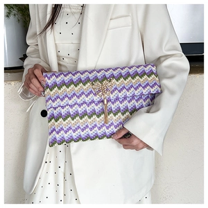 Detail of hand-woven straw envelope bag with purple wavy patterns and butterfly buckle