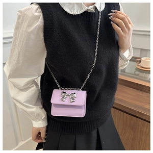 Detail of light purple mini crossbody bag with a silver bow and metal chain strap