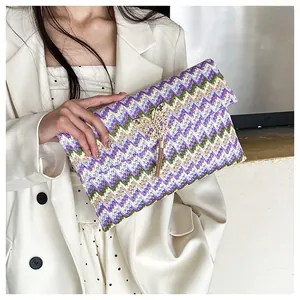 Detail of colorful woven envelope clutch featuring gold butterfly buckle and metal tassels
