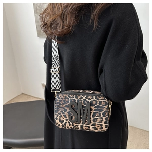 Detail showing leopard print crossbody bag with SM logo and geometric wide strap