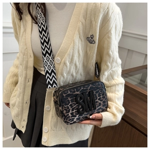 Detail of leopard print crossbody bag with black SM letter logo and wide woven strap