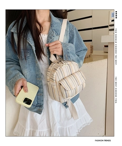 Detail of small striped canvas backpack with adjustable straps worn in a casual style