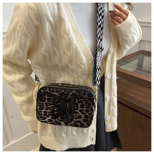 Detail of leopard print camera bag featuring SM logo and geometric wide strap