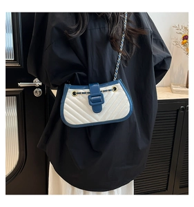 Détail du cuir matelassé et de la bandoulière en chaîne dorée sur un sac bicolore