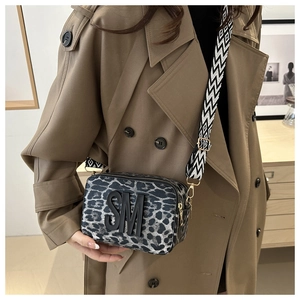Close-up of leopard print camera bag with 3D embossed logo and geometric strap