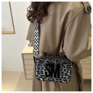 Detail of leopard print camera bag with SM logo and geometric strap on khaki trench coat