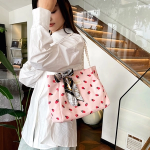 Pink corduroy strawberry tote bag with white woven handles and decorative scarf