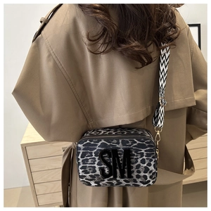 Close-up of leopard print camera bag with 3D SM logo and geometric wide shoulder strap