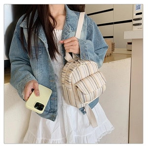 Detail of striped canvas crossbody bag worn by a model in a casual lifestyle setting