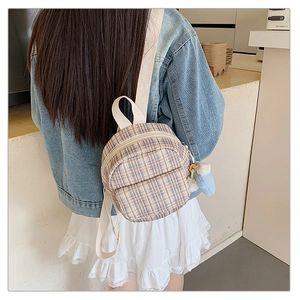 Detail of yellow and blue checkered mini backpack with cream straps and plush charm