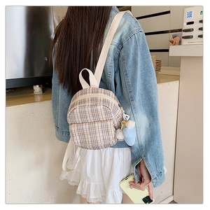 Close-up of a mini checkered backpack for women with a blue plush heart pendant detail