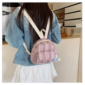 Detail of pink striped canvas mini backpack with cute plush charm and white straps