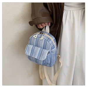 Close-up of mini blue striped canvas backpack with beige woven straps and front pocket