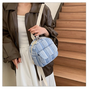 Detail of blue and white striped canvas backpack with front flap pocket and dual zippers