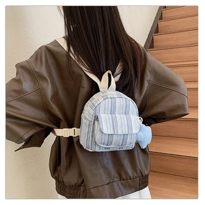 Detail of mini blue striped canvas backpack with star plush pendant on shoulder