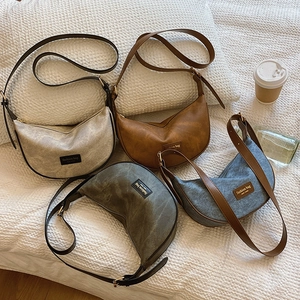 Minimalist crescent moon shoulder bags in four colors with adjustable straps on white texture