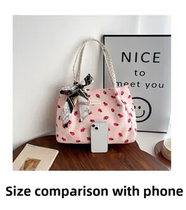 Detailed comparison of pink strawberry corduroy tote bag size with a smartphone