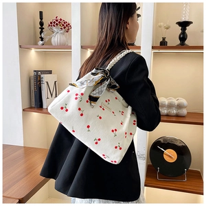 Detail of white corduroy tote bag with cherry prints and a decorative silk scarf bow