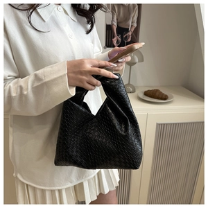 Detail of black woven leather texture on a minimalist hobo bag for stylish women