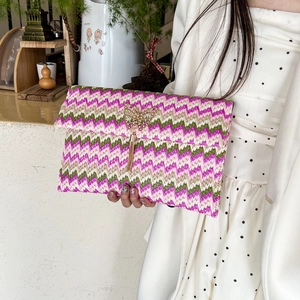 Colorful woven straw envelope clutch with golden butterfly buckle and fringe detail