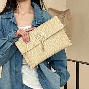 Beige straw envelope clutch with gold butterfly accent and long metallic tassels