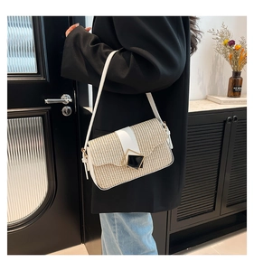 Détail du sac à bandoulière en paille tressée contrastée avec une boucle carrée dorée