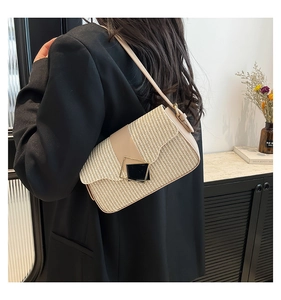 Détail du sac bandoulière en paille beige avec garniture en cuir et fermoir géométrique
