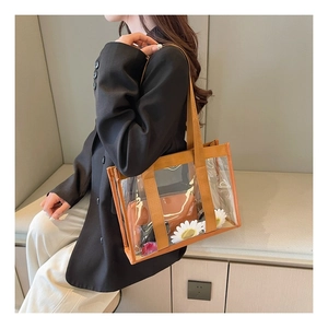 Detail of transparent PVC tote bag with brown canvas trim and inner pouch on model