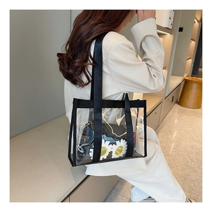 Detailed view of clear PVC tote bag with black trim and a floral daisy inner pouch