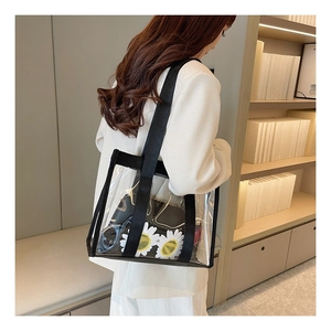 Modern clear transparent tote bag with black straps and inner pouch shown on shoulder
