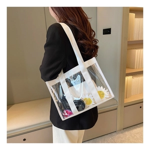 Detail of transparent large capacity tote bag with white straps worn by a model