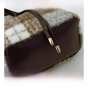 Detail of wool plaid fabric and smooth brown leather texture on a bucket bag