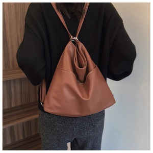 Detail view of brown leather triangular bag with soft texture and adjustable straps