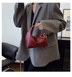 Close-up of wine red hobo bag showing embossed logo and sleek leather texture