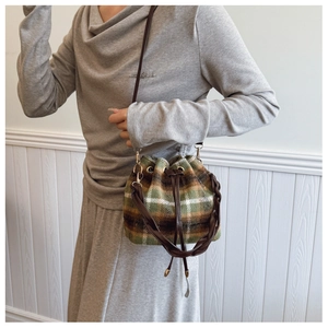 Detail of plaid wool bucket bag with drawstring closure and stylish woven handle