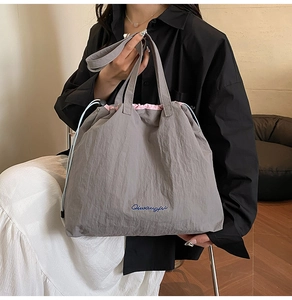 Détail du cabas en nylon gris avec doublure rose, cordon bleu et logo brodé