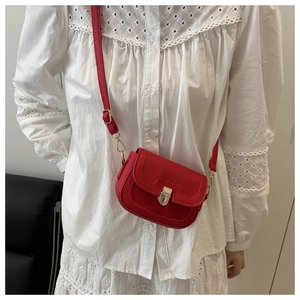 Detailed close-up of red lychee texture crossbody bag with gold metallic lock closure