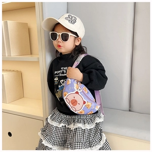 Close-up of kids purple cartoon bear crossbody bag worn by a young girl outdoors
