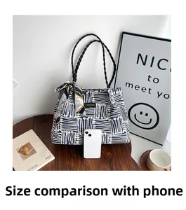 Detailed comparison of the striped tote bag with a smartphone to show compact size