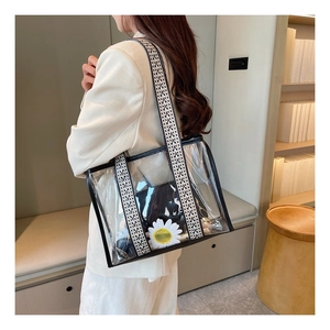 Detail of transparent PVC tote bag with white daisy print and woven shoulder strap
