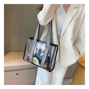 Transparent PVC tote bag with daisy detail and woven strap shown on a white suit model