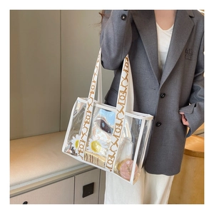 Close-up of clear PVC tote bag showing large capacity and geometric canvas shoulder strap