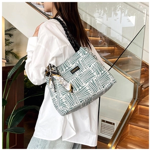 Detailed view of striped woven tote bag with silk scarf and central fashion label